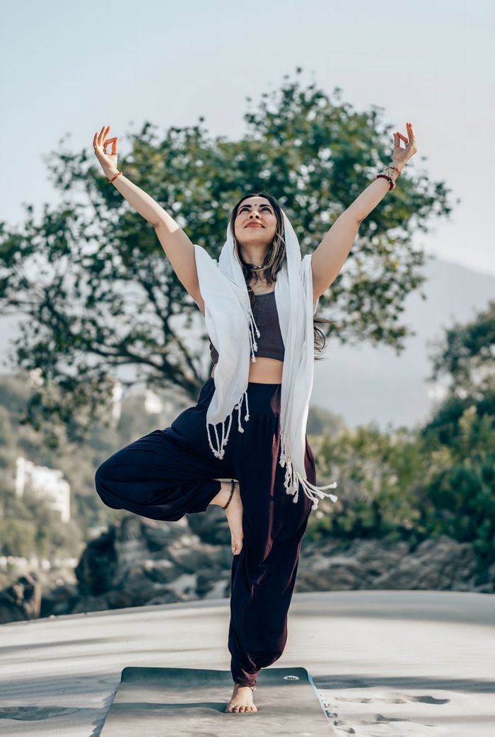 Woman practicing yoga tree pose outdoors in serene nature scene.